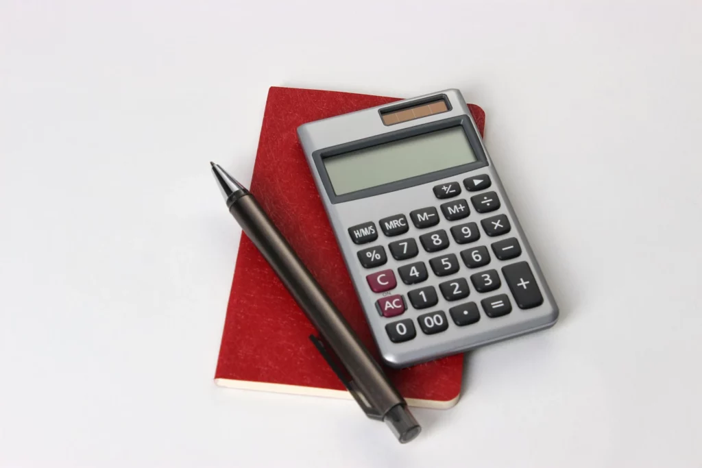 a calculator and pen on a red notebook to fix the Tunisia Tax Value